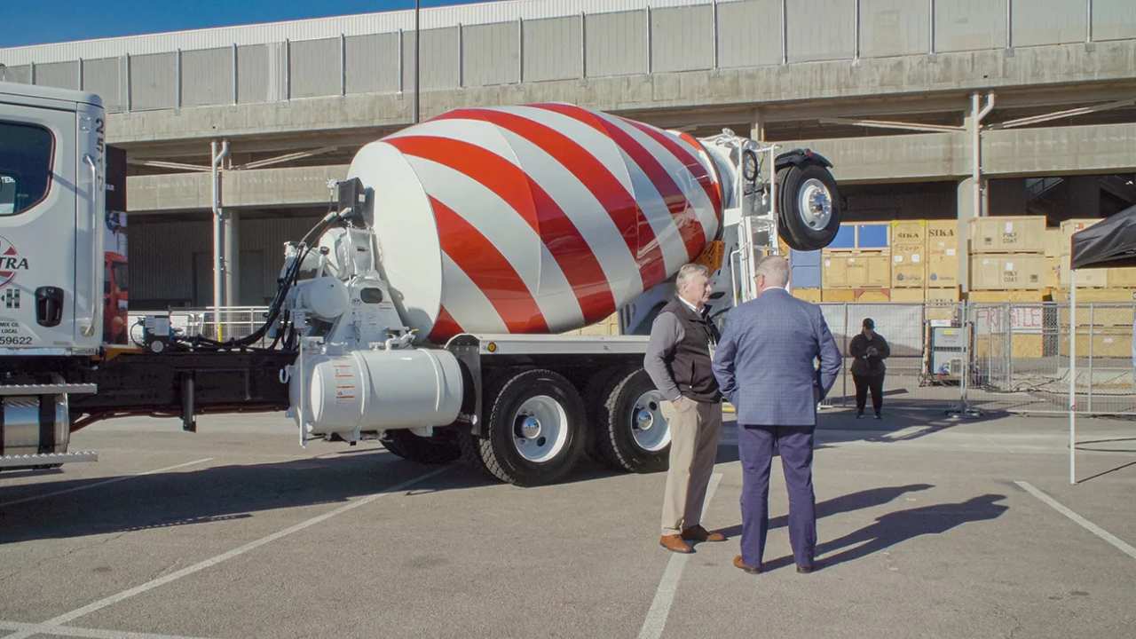 two men talking next to a cement mixer